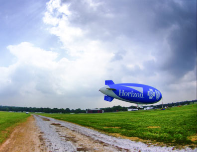 a blimp flying over a dirt road