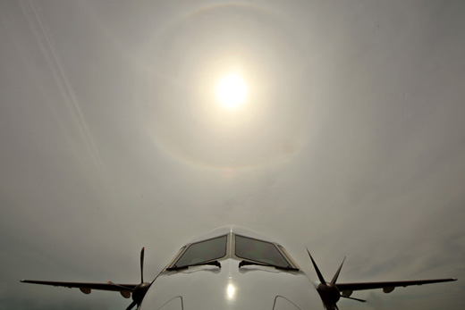 the front of a plane with the sun in the background