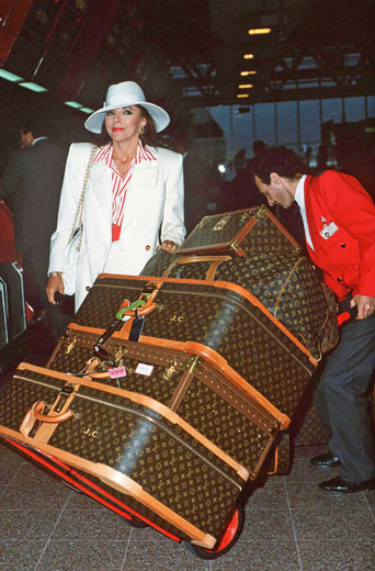 a woman pushing a stack of luggage