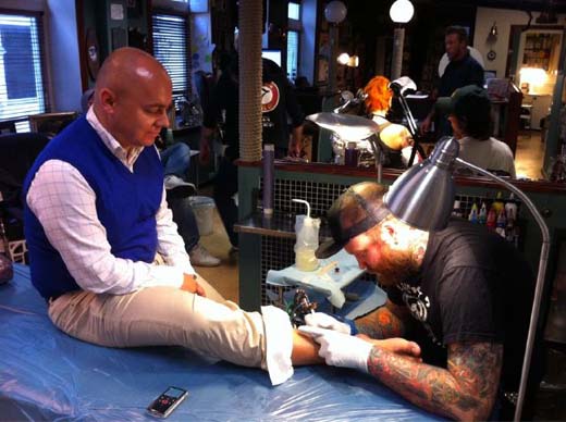 a man getting a tattoo on a man's leg